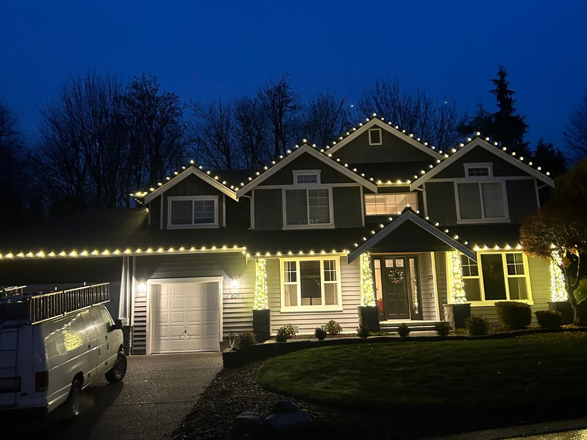 Home with custom-fitted warm white Christmas lights at dusk